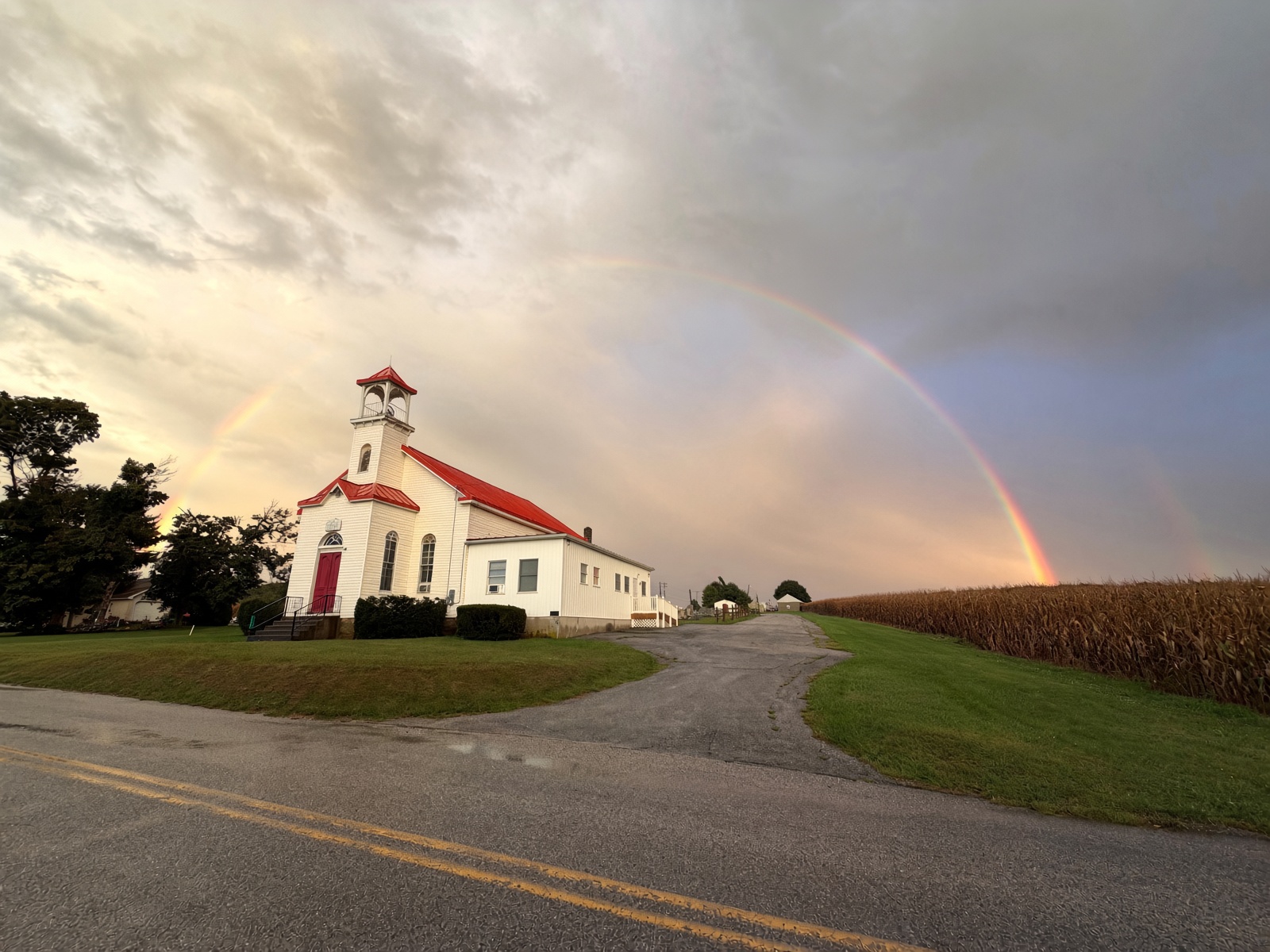 White church with a red roof under a rainbow at Grace Chapel